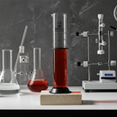 Laboratory setup with a TN Lab 1000ml 1L borosilicate glass 3.3 graduated cylinder with plastic guards on a gray background
